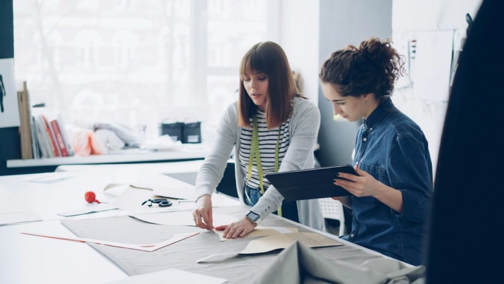 Deux collaboratrices relisent des maquettes sur une table de travail