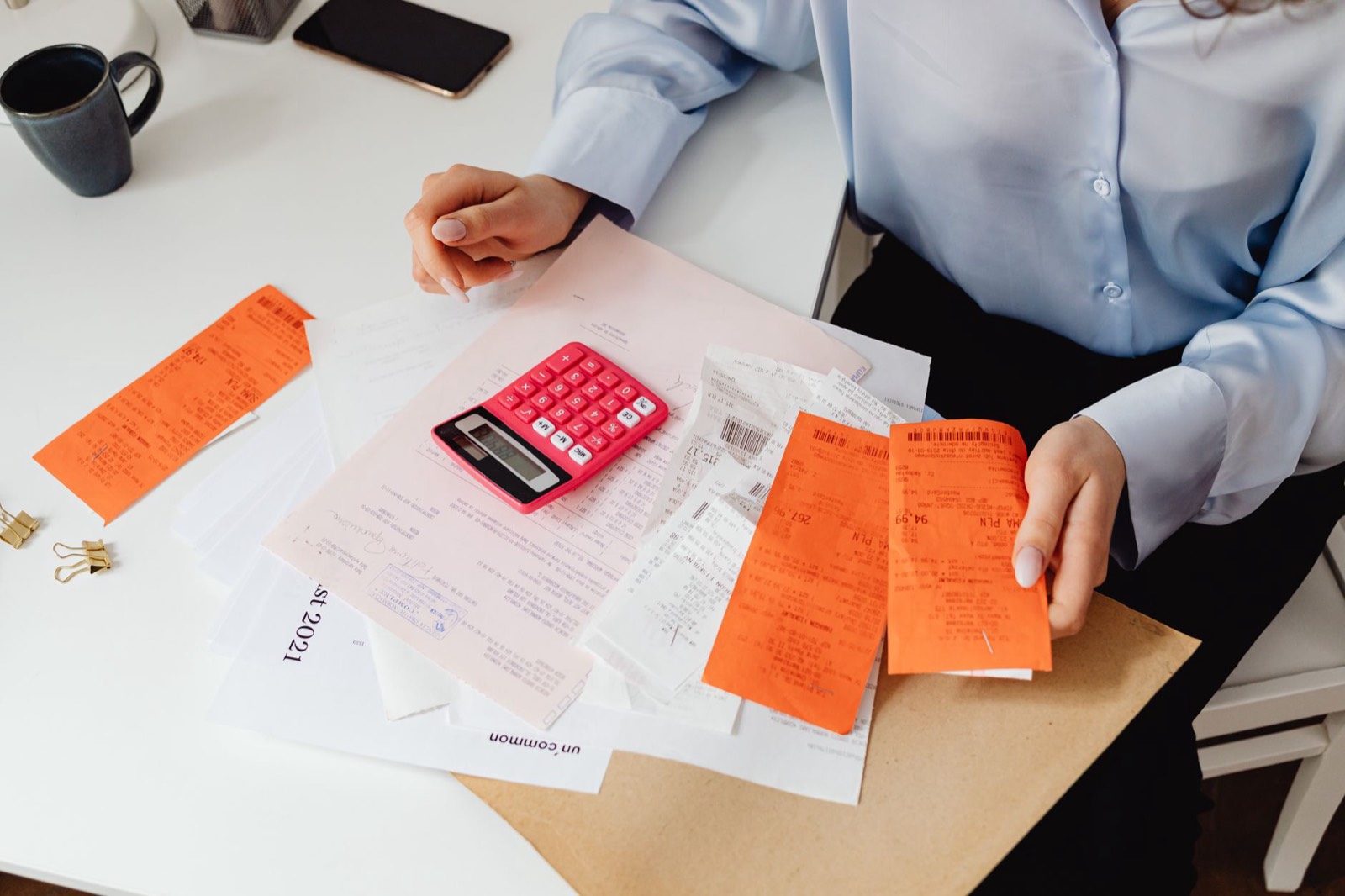 Freelance créateur de contenu organisant ses factures et reçus avec une calculatrice sur un bureau