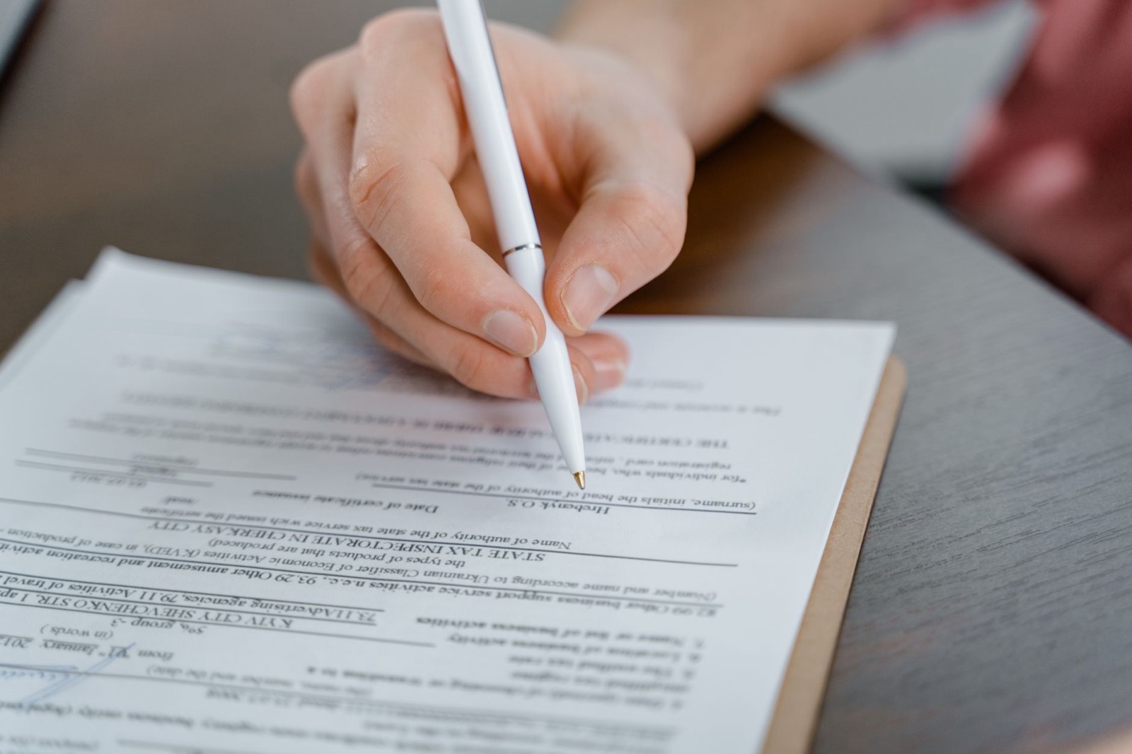 Une main signe un devis posé sur un bureau, stylo au-dessus de la ligne de signature